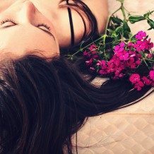 woman lying next to flowers with sexy hair