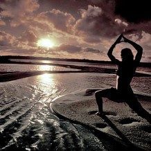 person doing yoga on the beach at sunrise