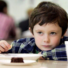 Young kid sitting at lunch table with malnutrition