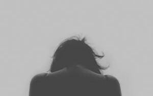 Black, White, and Grey Toned Photo with Person with Hunched Back Facing Away from the Camera 