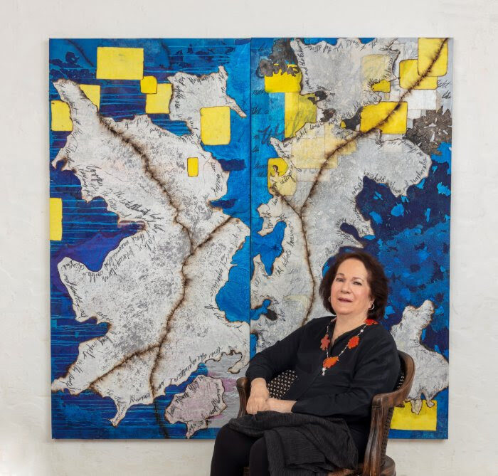 Mira Lehr posing in front of blue, yellow, and grey artwork